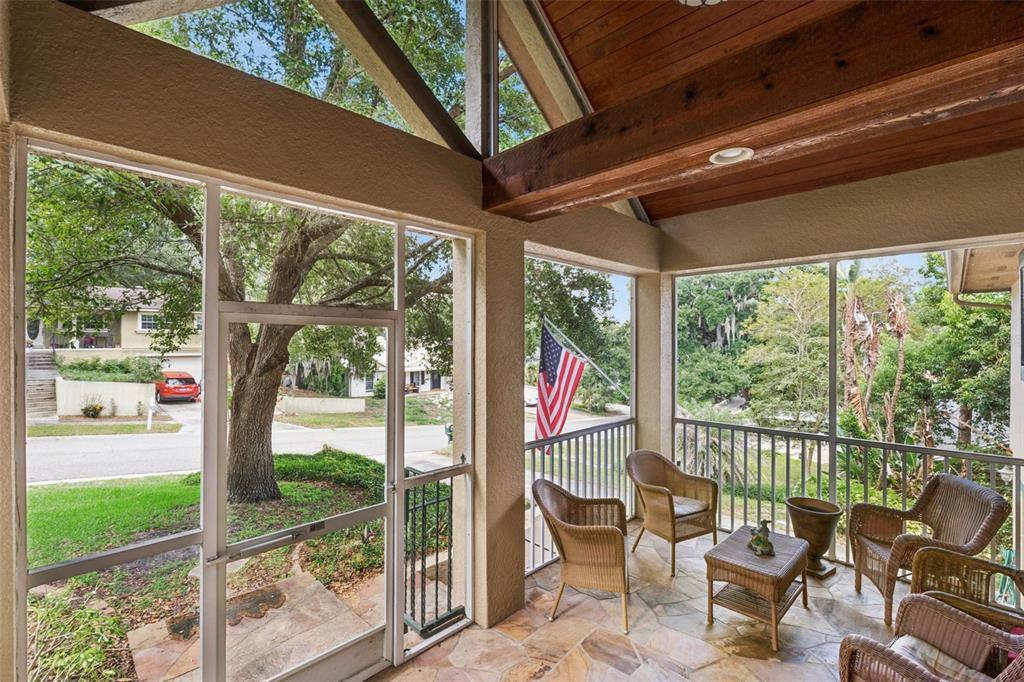 A screened-in porch features a stone floor, wood-beamed ceiling, and views of a residential street — 324 HICKORY COURT, APOPKA, FL