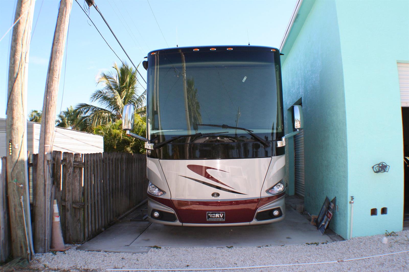 A large recreational vehicle is parked in a narrow space between a fence and building — 142 Eldorado Street, Fort Pierce FL 34949, FORT PIERCE, FL