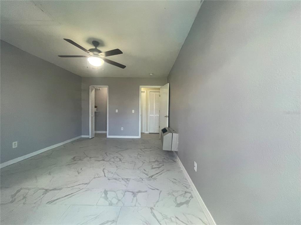 An empty room features gray walls, a ceiling fan, and white marble-patterned tile flooring — 227 ORCHID DRIVE, DAVENPORT, FL