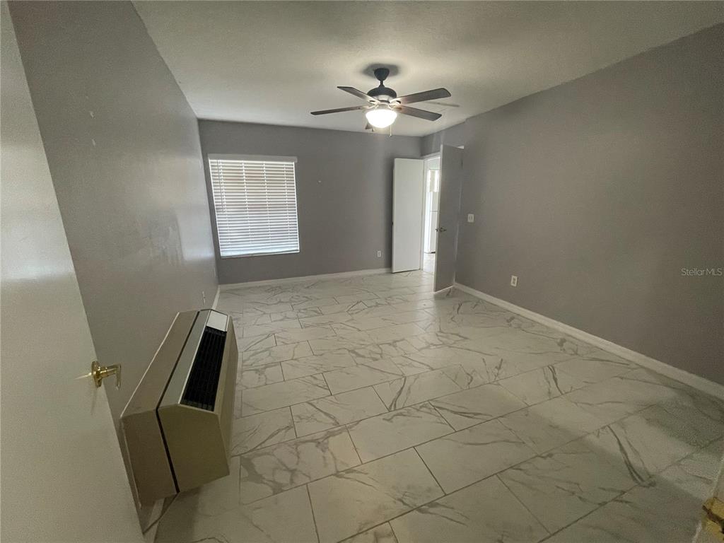 A room with gray walls, white marble-look tile flooring, a ceiling fan, and a wall-mounted AC — 227 ORCHID DRIVE, DAVENPORT, FL