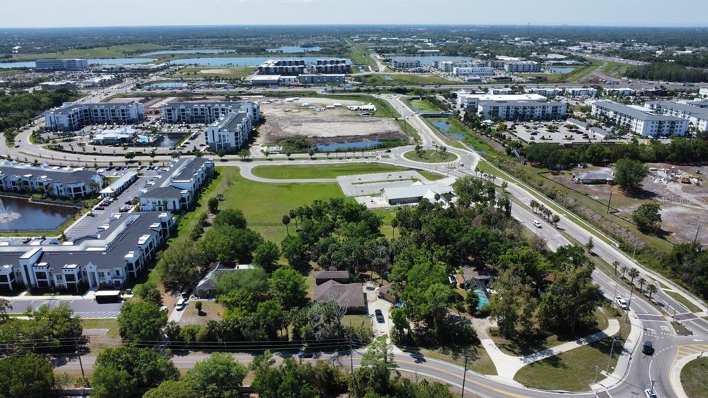 An aerial view shows residential buildings, a roundabout, and wooded lots near a main road — 6480 RICHARDSON ROAD, SARASOTA, FL