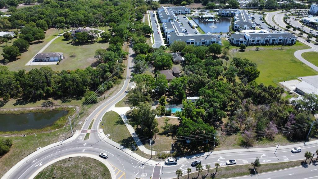 An aerial view shows a residential property with a pool surrounded by trees and roads — 6480 RICHARDSON ROAD, SARASOTA, FL