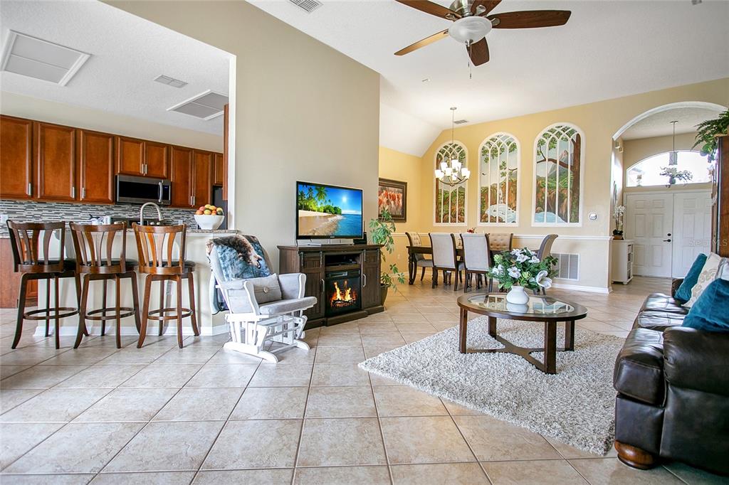 An open-concept living and dining area features tile flooring, a fireplace, and arched wall murals — 442 HOME GROVE DRIVE, WINTER GARDEN, FL