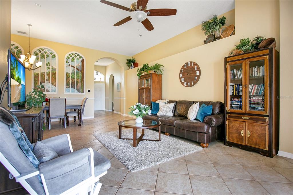 A living room features tile flooring, a leather sofa, a wall clock, and arched wall murals — 442 HOME GROVE DRIVE, WINTER GARDEN, FL