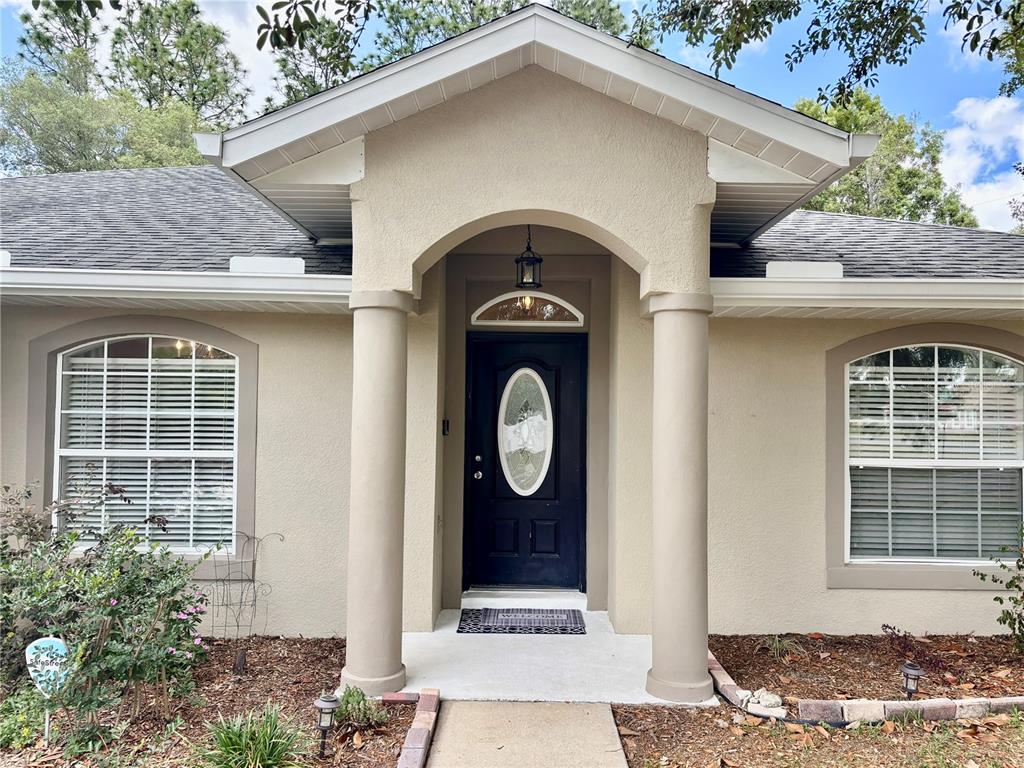 The exterior of a beige house features a covered entryway with two columns and a door — 6021 SW 131ST LANE UNIT 10, OCALA, FL