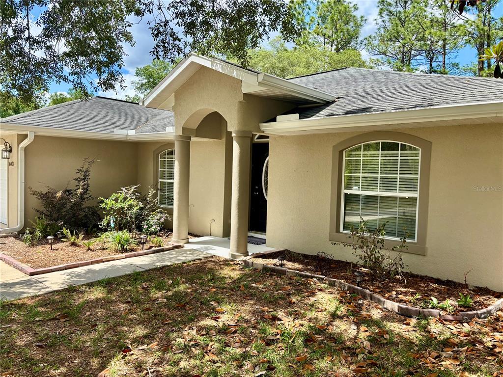 The exterior of a single-story house features a covered entryway with columns and landscaping — 6021 SW 131ST LANE UNIT 10, OCALA, FL