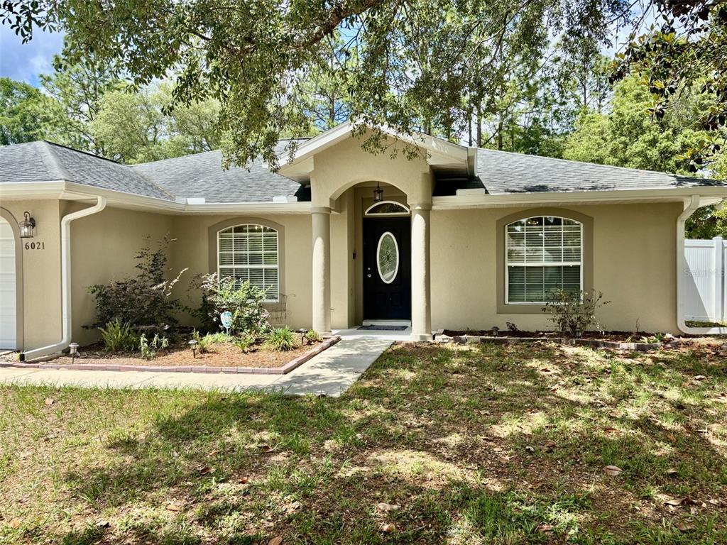 A single-story house with a beige stucco exterior, arched entryway, and two front windows — 6021 SW 131ST LANE UNIT 10, OCALA, FL