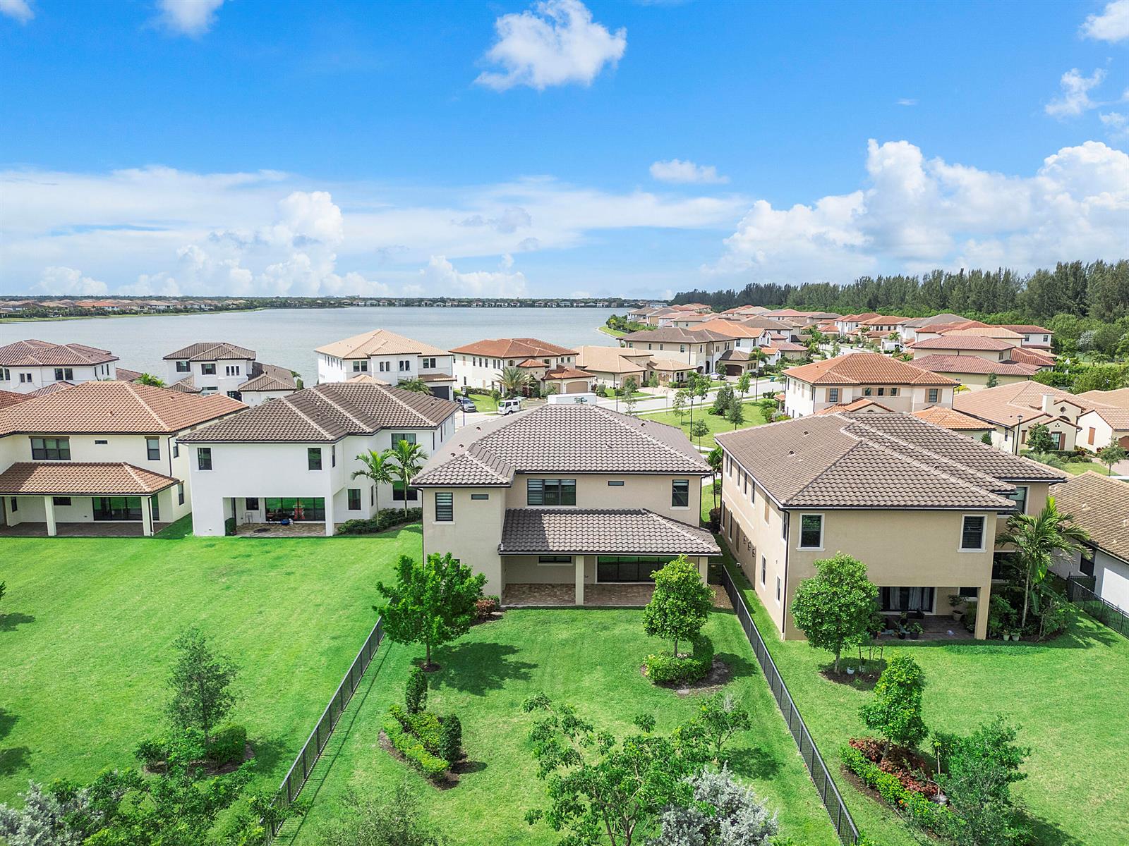 An aerial view shows suburban houses with tiled roofs and backyards bordering a large lake — 12745 Bayside Court, Parkland FL 33076, PARKLAND, FL