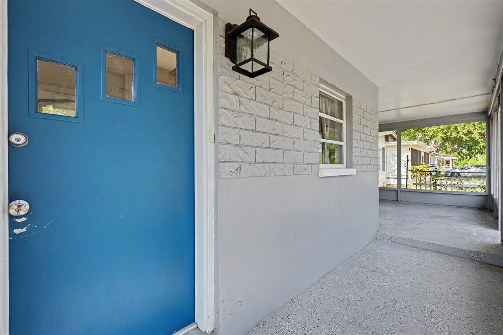 A blue front door opens onto a covered porch with gray painted brick walls — 29 6TH AVENUE SE, LARGO, FL