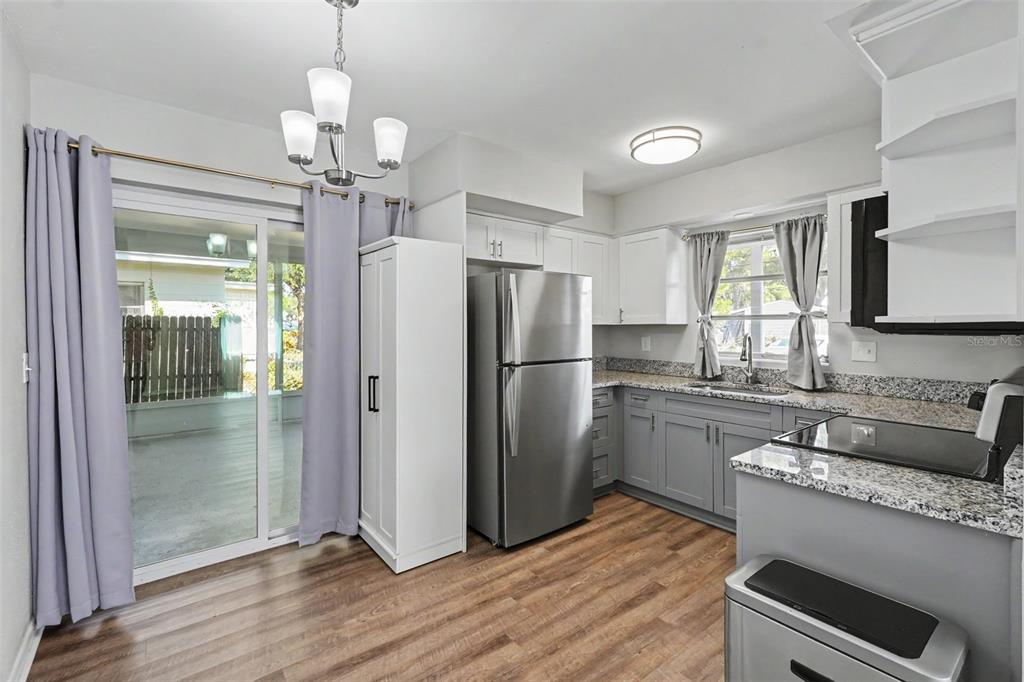 A kitchen with gray cabinets, granite countertops, stainless steel appliances, and a sliding glass door — 29 6TH AVENUE SE, LARGO, FL