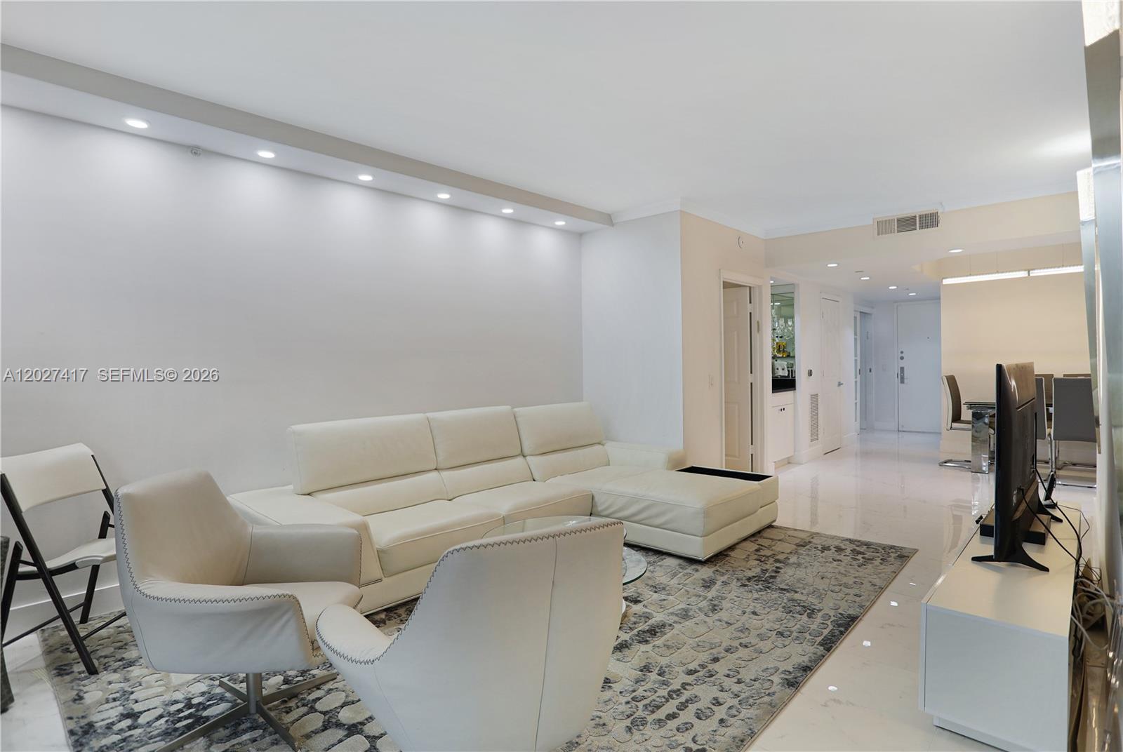 A living room features a white sectional sofa, two armchairs, and a patterned area rug — 4775 COLLINS AV # 1804, Miami Beach FL 33140, MIAMI BEACH, FL