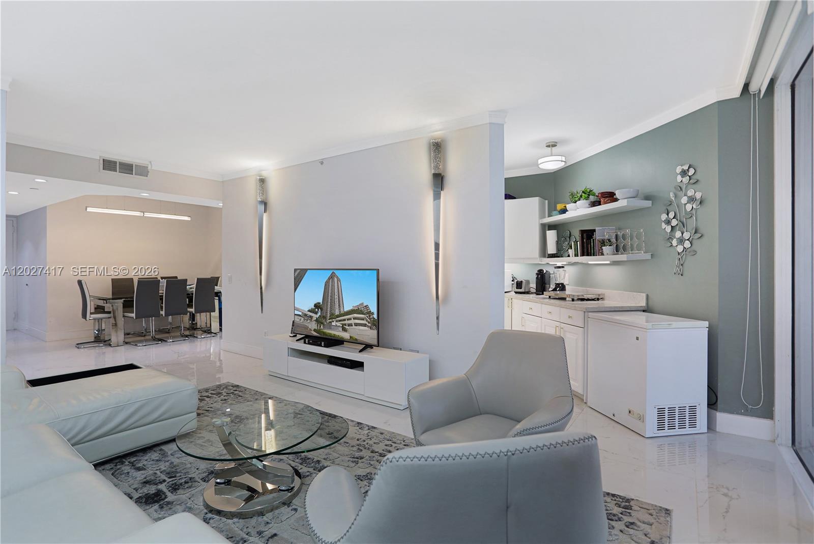 A living room features a white media console, glass coffee table, and adjacent kitchen area — 4775 COLLINS AV # 1804, Miami Beach FL 33140, MIAMI BEACH, FL
