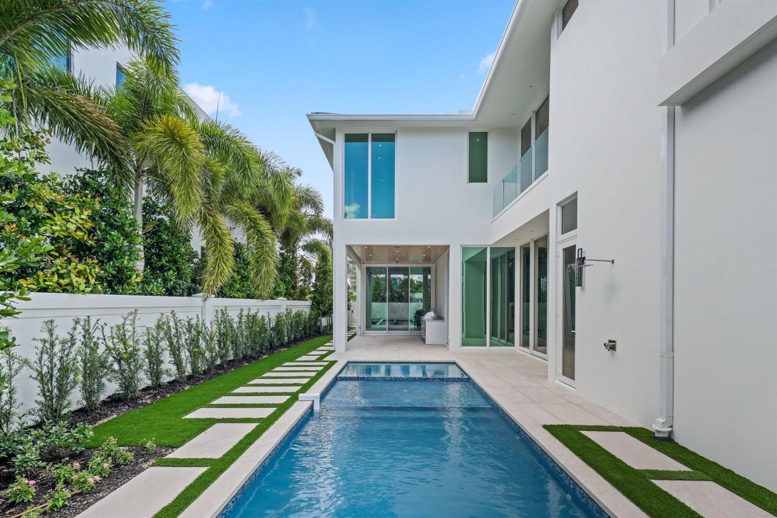 A modern white house features a rectangular swimming pool and a landscaped side yard — 330 Grove Place, Delray Beach FL 33444, DELRAY BEACH, FL