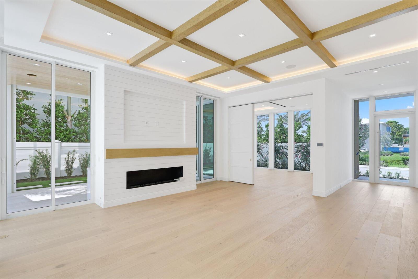 A bright living room features light wood flooring, a coffered ceiling, and a shiplap fireplace — 330 Grove Place, Delray Beach FL 33444, DELRAY BEACH, FL