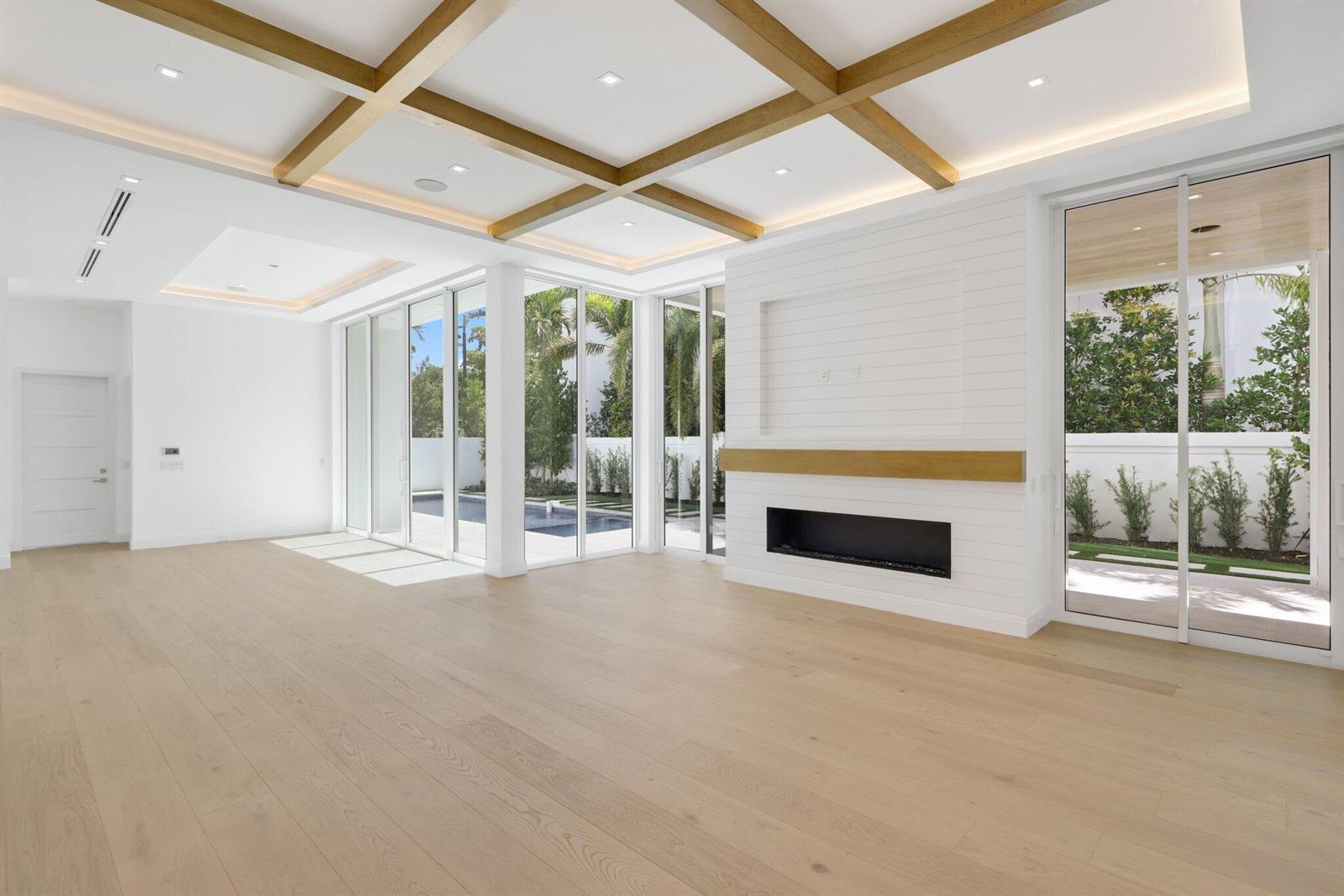 A bright living room features light wood floors, a coffered ceiling, and a modern fireplace — 330 Grove Place, Delray Beach FL 33444, DELRAY BEACH, FL