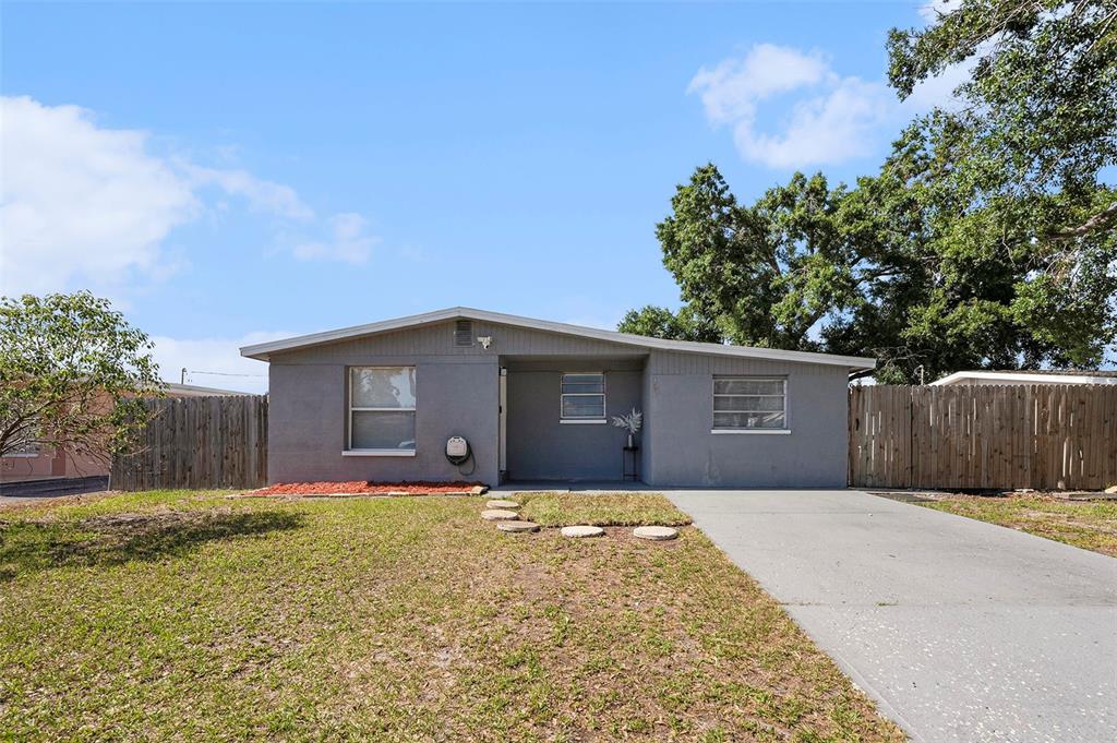 A single-story gray house with a concrete driveway and a wooden fence — 4521 W NORTH STREET, TAMPA, FL