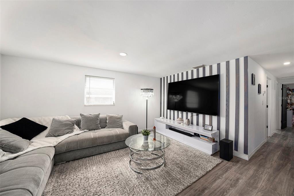 A living room features a grey sectional sofa, a glass coffee table, and a striped accent wall — 4521 W NORTH STREET, TAMPA, FL