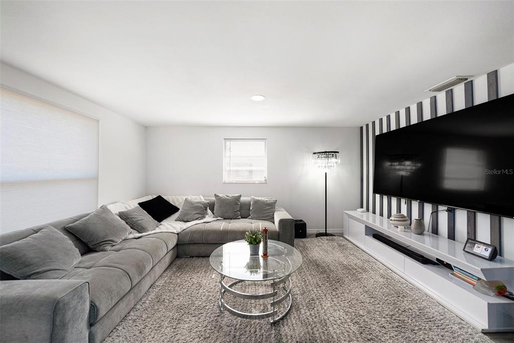 A living room features a grey sectional sofa, a glass coffee table, and a striped wall — 4521 W NORTH STREET, TAMPA, FL
