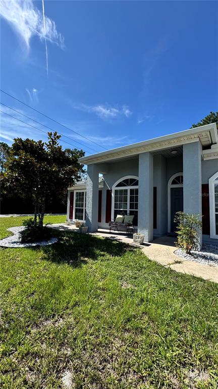 A single-story house exterior features a covered front porch, light gray siding, and red shutters — 1 PRESIDENT LANE, PALM COAST, FL