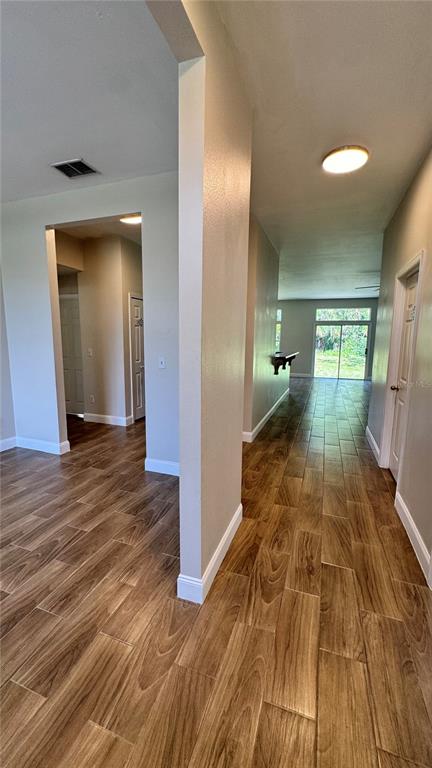 A hallway with wood-look tile flooring leads toward a living area with sliding glass doors — 1 PRESIDENT LANE, PALM COAST, FL