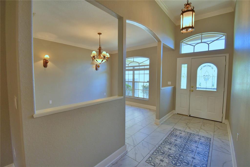 An entryway with tile flooring, a front door with a sidelight, and an adjacent dining area — 239 GOLF AIRE BOULEVARD, WINTER HAVEN, FL