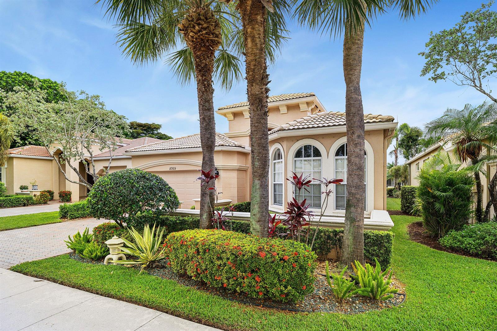 A tan stucco house with a tile roof and palm trees in the front yard — 8769 Via Grande E, Wellington FL 33411, WELLINGTON, FL