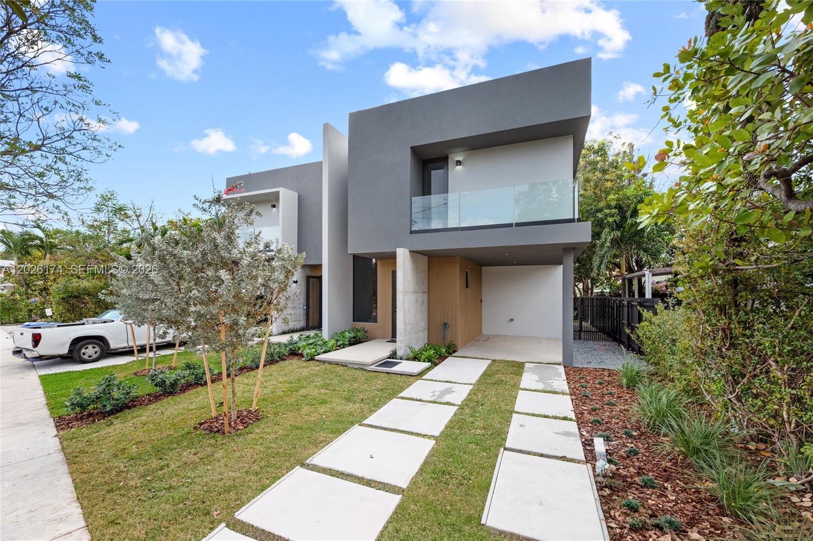 A modern two-story duplex with a concrete driveway, glass balcony, and gray exterior walls — 2980 SW 2nd St, Miami FL 33135, MIAMI, FL