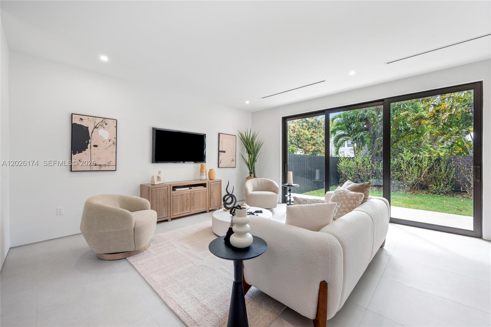 A modern living room features a white sofa, two armchairs, a television, and sliding glass doors — 2980 SW 2nd St, Miami FL 33135, MIAMI, FL