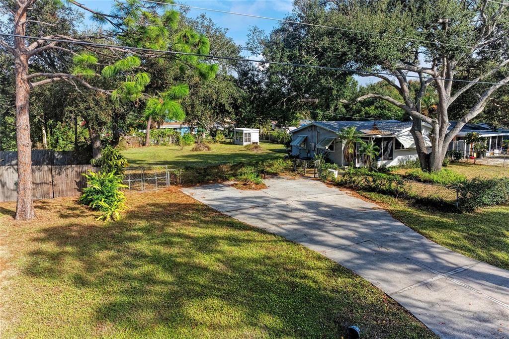 A concrete driveway leads to a single-story house surrounded by trees and a grassy yard — 0 PARK ROAD, VENICE, FL
