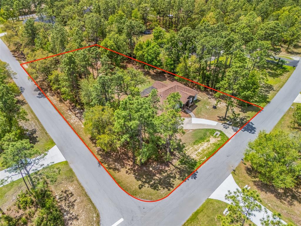 An aerial view shows a house situated on a corner lot surrounded by trees — 2187 COUNTY ROAD 243C, WILDWOOD, FL