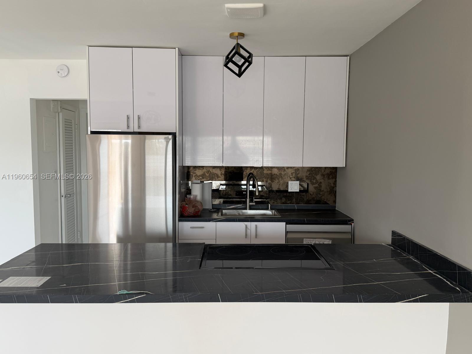 A kitchen features white cabinets, a black marble-patterned countertop, and stainless steel appliances — 725 SW 11th Ave # 17F, Hallandale Beach FL 33009, HALLANDALE BEACH, FL