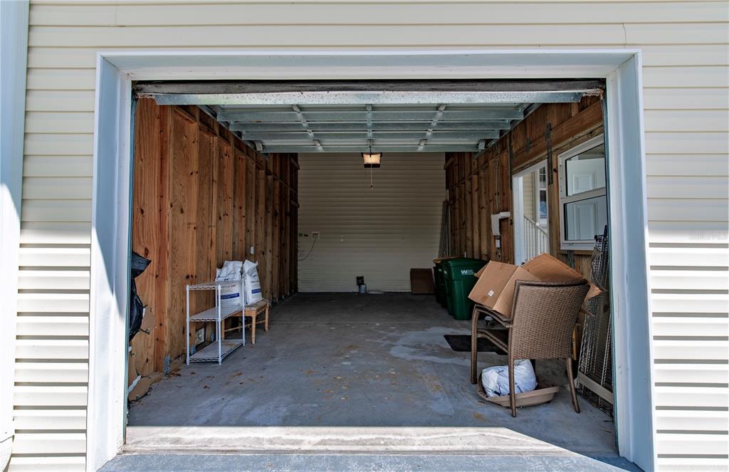 An open garage features unfinished wood-paneled walls, a concrete floor, and a single light fixture — 22 FREEMAN AVENUE, PUNTA GORDA, FL