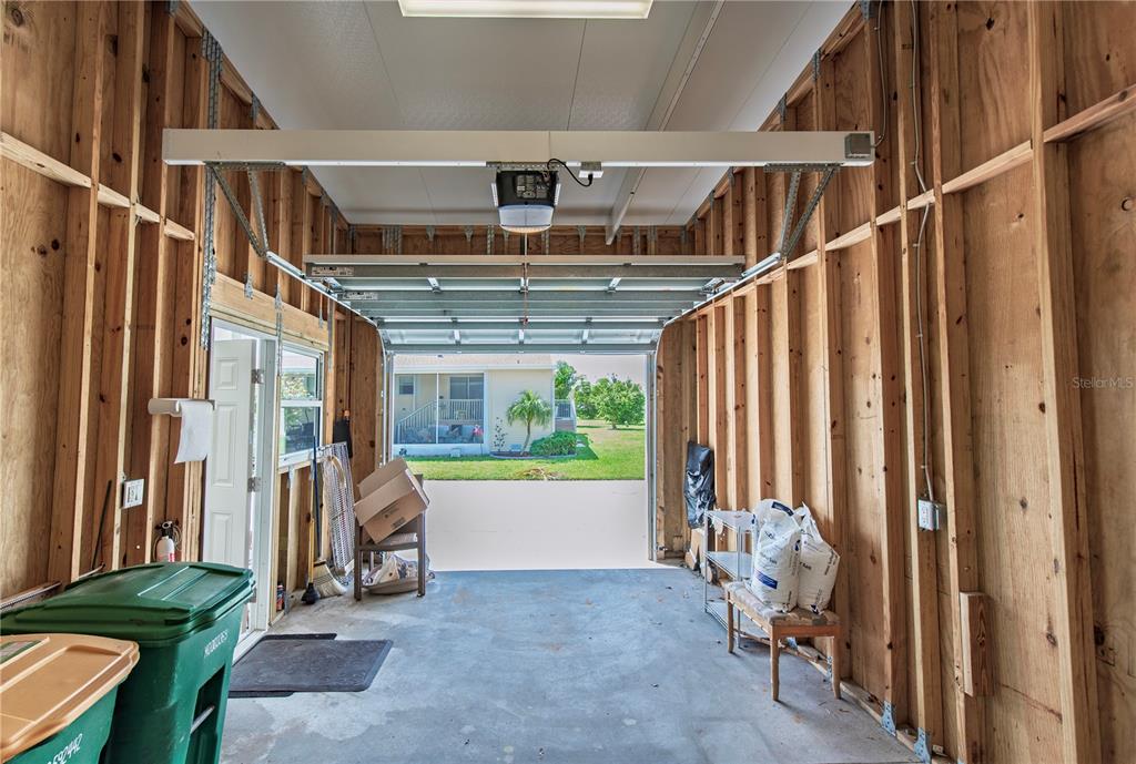 An unfinished garage with exposed wooden wall studs, a concrete floor, and an open door — 22 FREEMAN AVENUE, PUNTA GORDA, FL