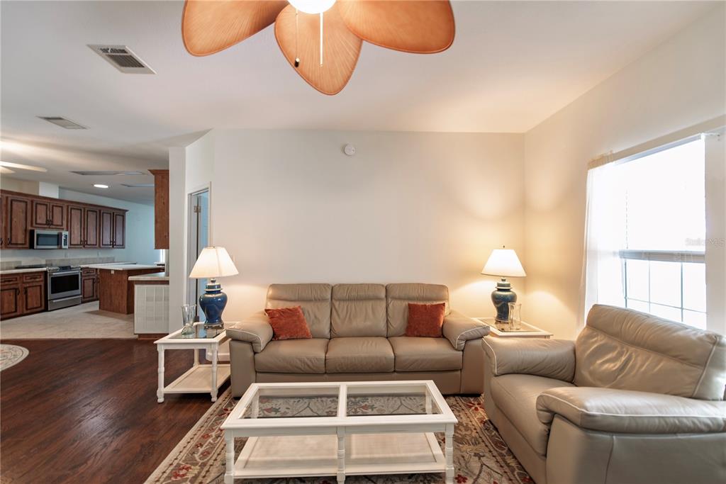 A living room with a beige sofa, matching armchair, white coffee table, and ceiling fan — 22 FREEMAN AVENUE, PUNTA GORDA, FL