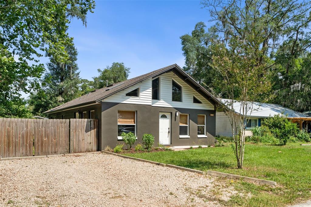 A single-story house with a dark gray exterior, white siding, and a gravel driveway — 3177 NW 9TH TERRACE, GAINESVILLE, FL