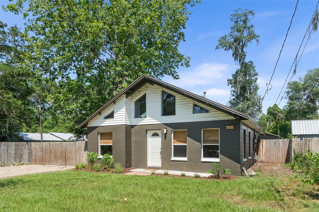 A single-story house with a dark brown exterior, white siding, and a gabled roof — 3177 NW 9TH TERRACE, GAINESVILLE, FL