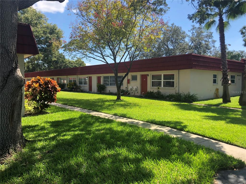 A single-story apartment building with a red roof and a sidewalk across a lawn — 5860 38TH AVENUE N UNIT 29, ST PETERSBURG, FL