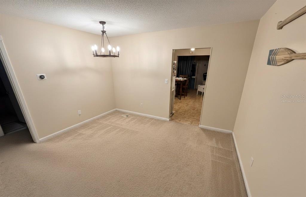 This dining room features beige carpet, a chandelier, and an open doorway to another room — 5860 38TH AVENUE N UNIT 29, ST PETERSBURG, FL