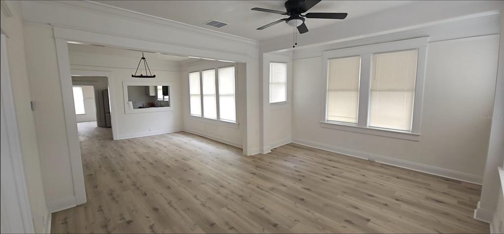 An open-concept living and dining area features light wood-look flooring, white walls, and large windows — 2312 E 8TH AVENUE, TAMPA, FL