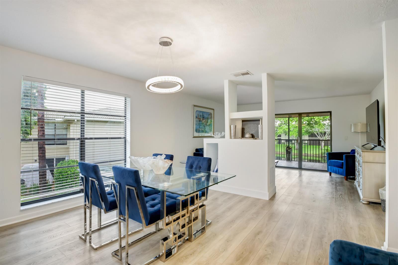 A dining area with a glass table and blue chairs sits beside a living room — BOYNTON BEACH, FL