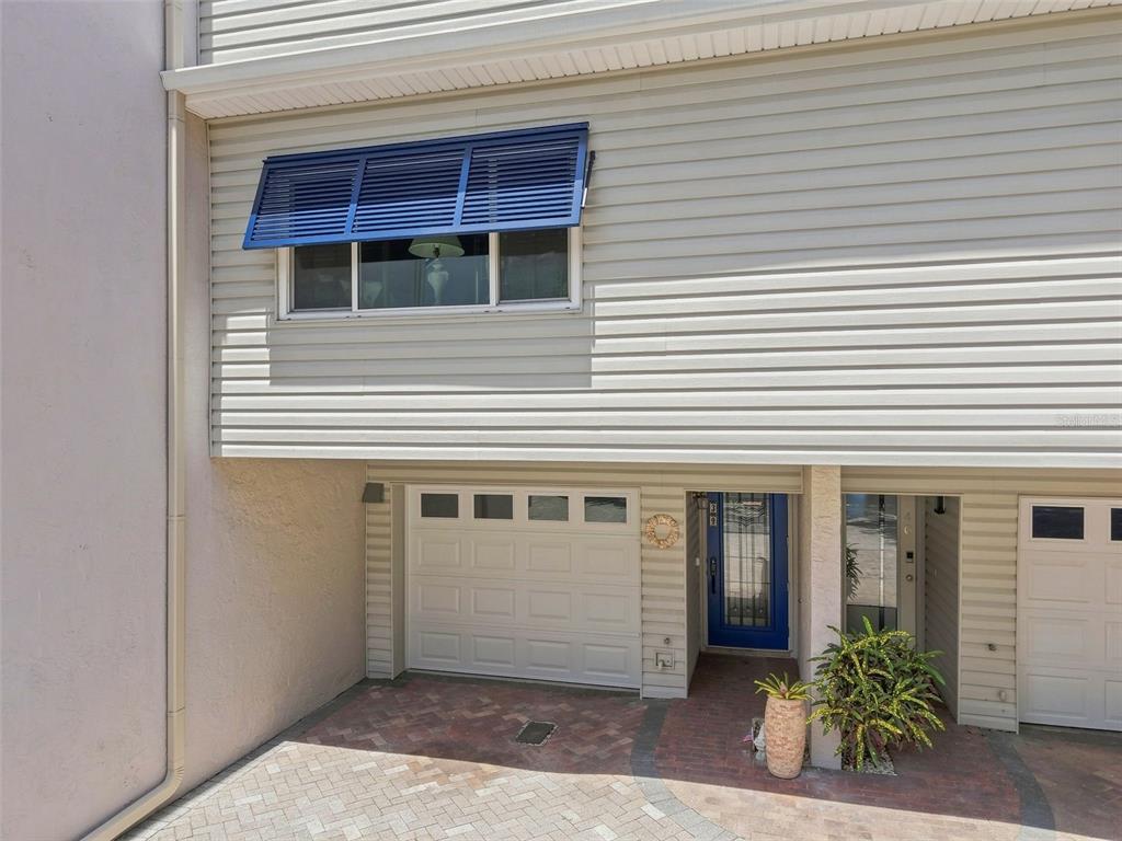 The exterior of a townhouse features a garage, a blue front door, and a window — 1375 PINELLAS BAYWAY S UNIT 39, TIERRA VERDE, FL