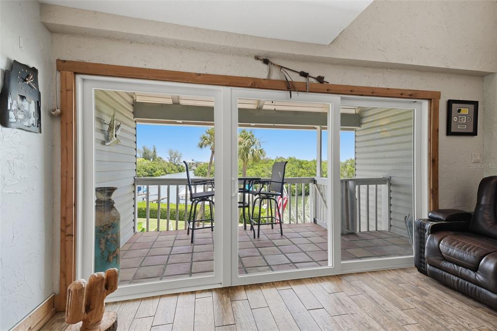 A living room with wood-look tile floors features large sliding glass doors opening to a balcony — 1375 PINELLAS BAYWAY S UNIT 39, TIERRA VERDE, FL