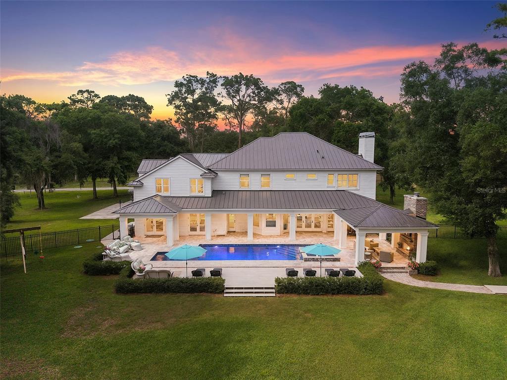 An aerial view of a two-story white house with a pool and covered patio — 18562 COUNCIL CREST DRIVE, ODESSA, FL
