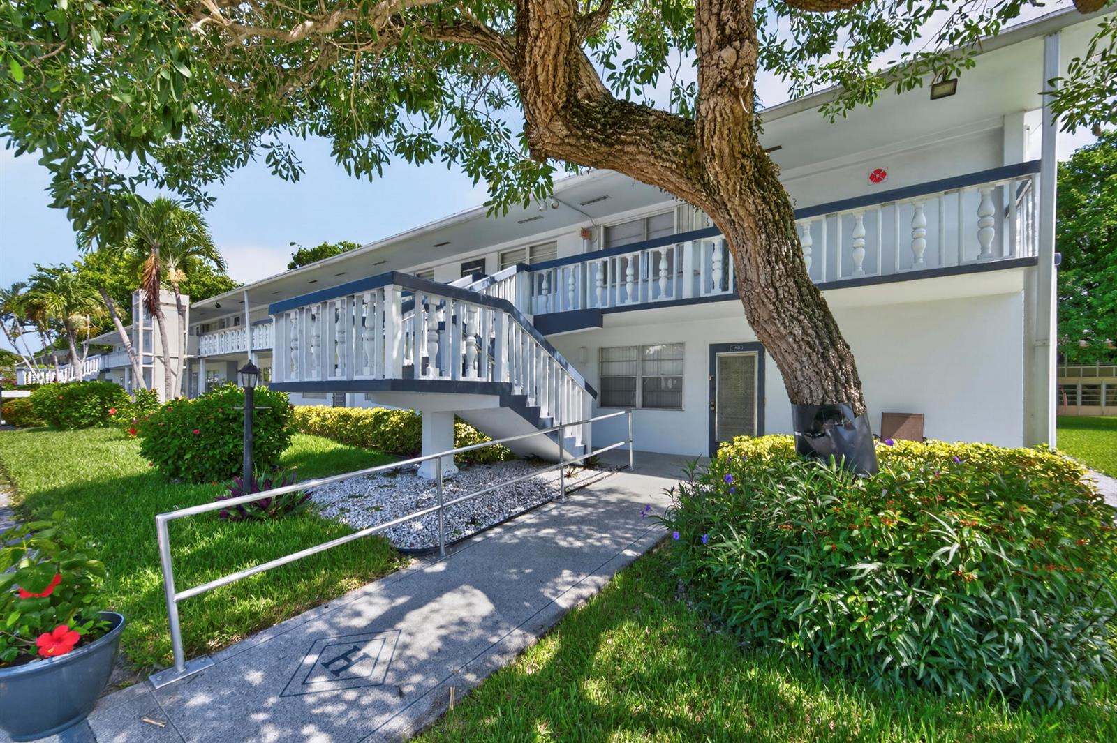 A two-story apartment building exterior features a white staircase leading to an upper balcony — 176 Upminster H # 176, Deerfield Beach FL 33442, DEERFIELD BEACH, FL