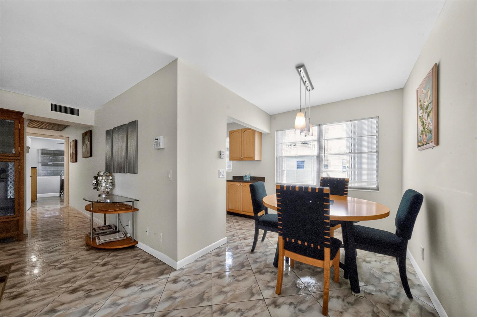 A dining area features a round wooden table, dark chairs, and light-colored tile flooring — 176 Upminster H # 176, Deerfield Beach FL 33442, DEERFIELD BEACH, FL