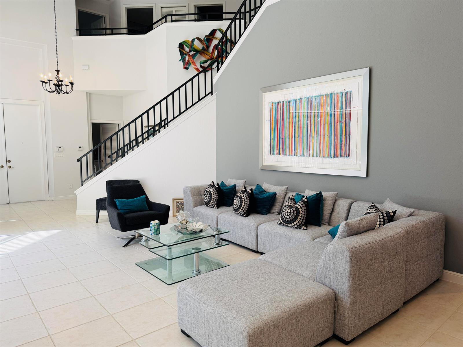 A modern living room features a gray sectional sofa, glass coffee table, and a staircase — 4285 NW 62nd Road, Boca Raton FL 33496, BOCA RATON, FL