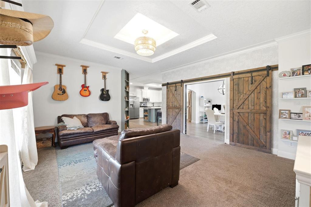 A living room features brown leather furniture, three wall-mounted guitars, and sliding barn doors — 12275 LAKELAND ACRES, LAKELAND, FL