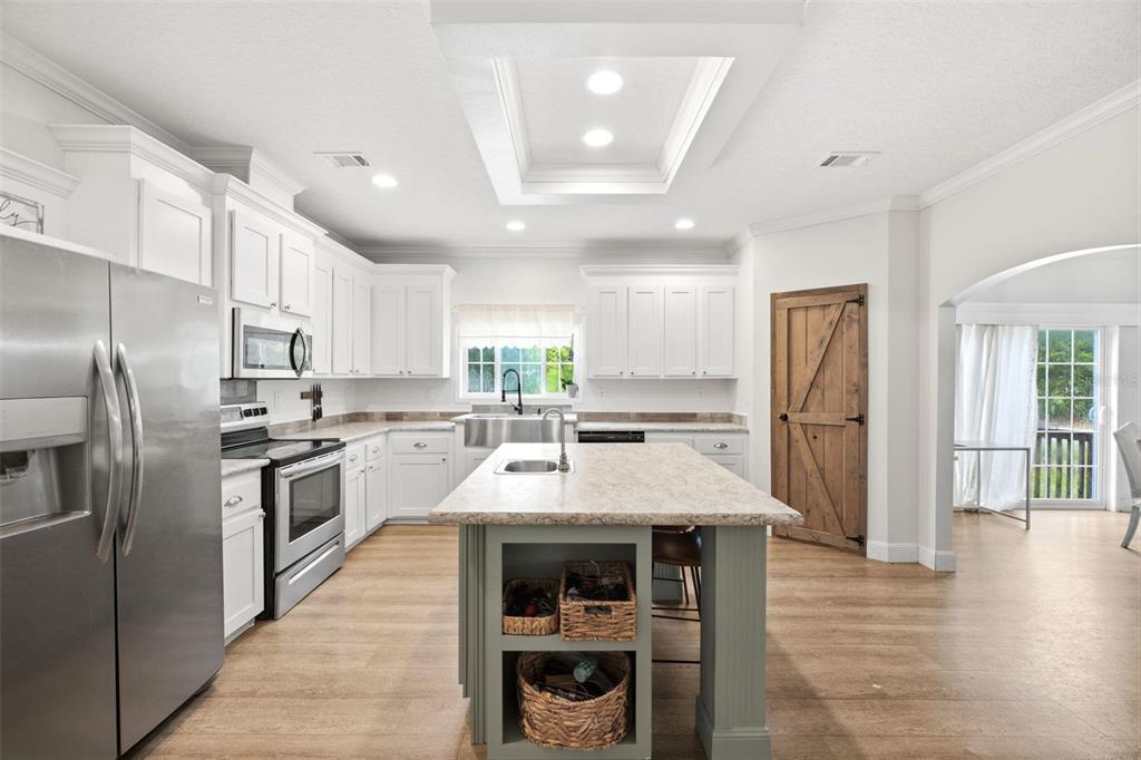 A kitchen with white cabinets, a central island, stainless steel appliances, and a barn door — 12275 LAKELAND ACRES, LAKELAND, FL