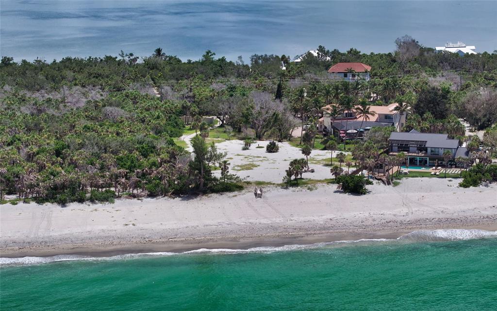 An aerial view of a coastal property featuring a sandy beach, lush vegetation, and houses — 6160 MANASOTA KEY ROAD, ENGLEWOOD, FL