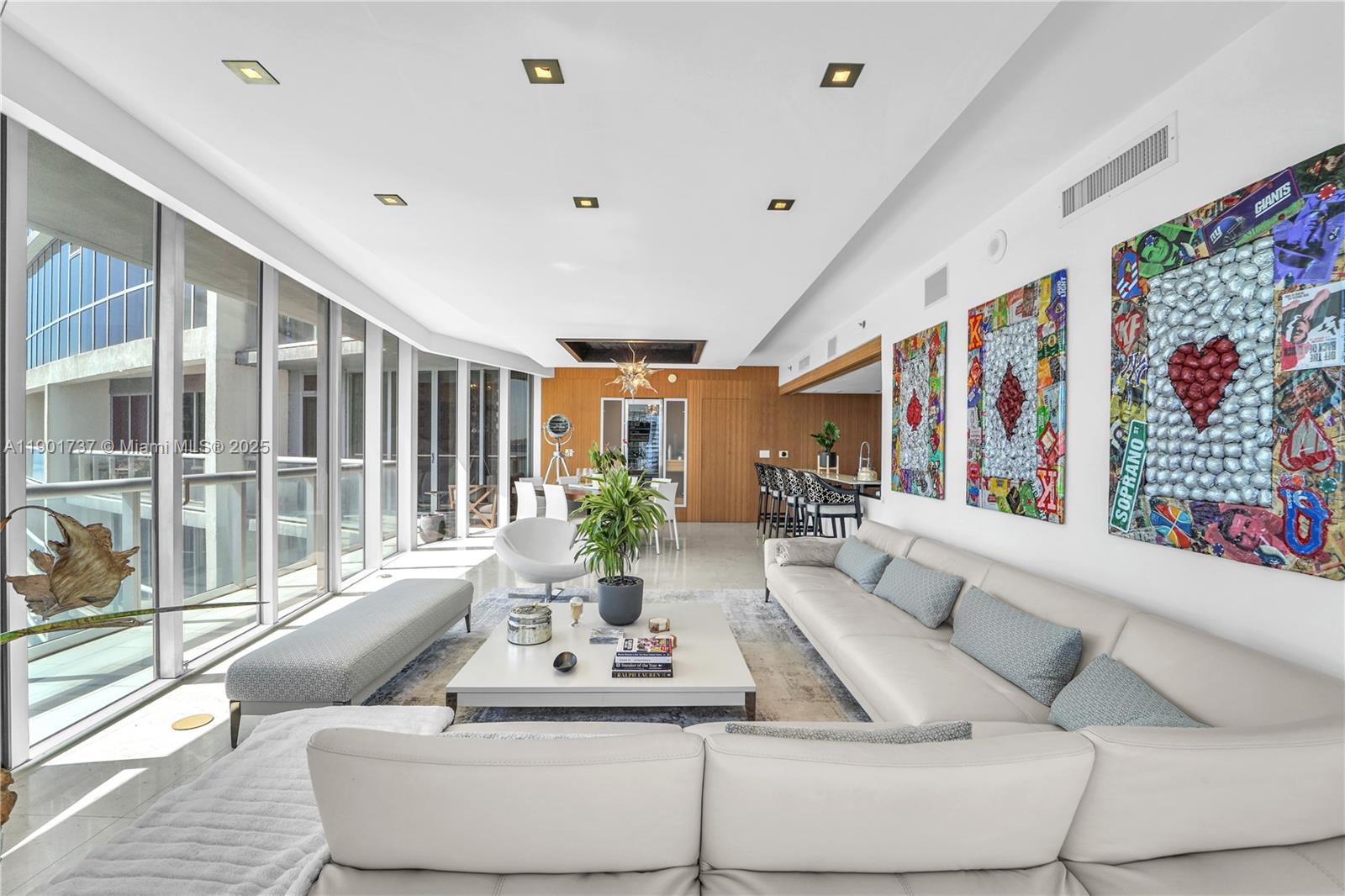 A modern living room features a white sectional sofa, a coffee table, and colorful wall art — 465 Brickell Ave # 1001, Miami FL 33131, MIAMI, FL